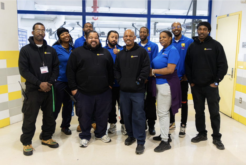 HCZ Facilities Team in uniforms standing in lobby of Promise Academy building.